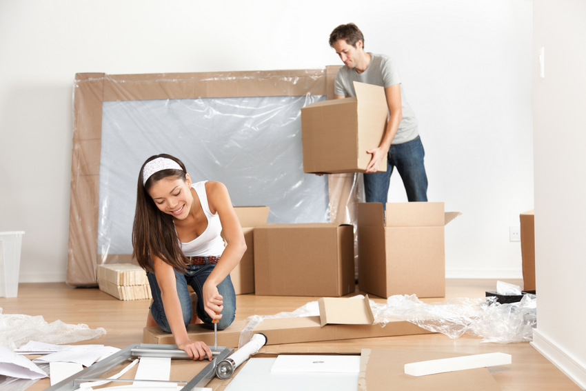 Couple moving in new home house. Young interracial couple in moving in mess. Asian woman, Caucasian man.