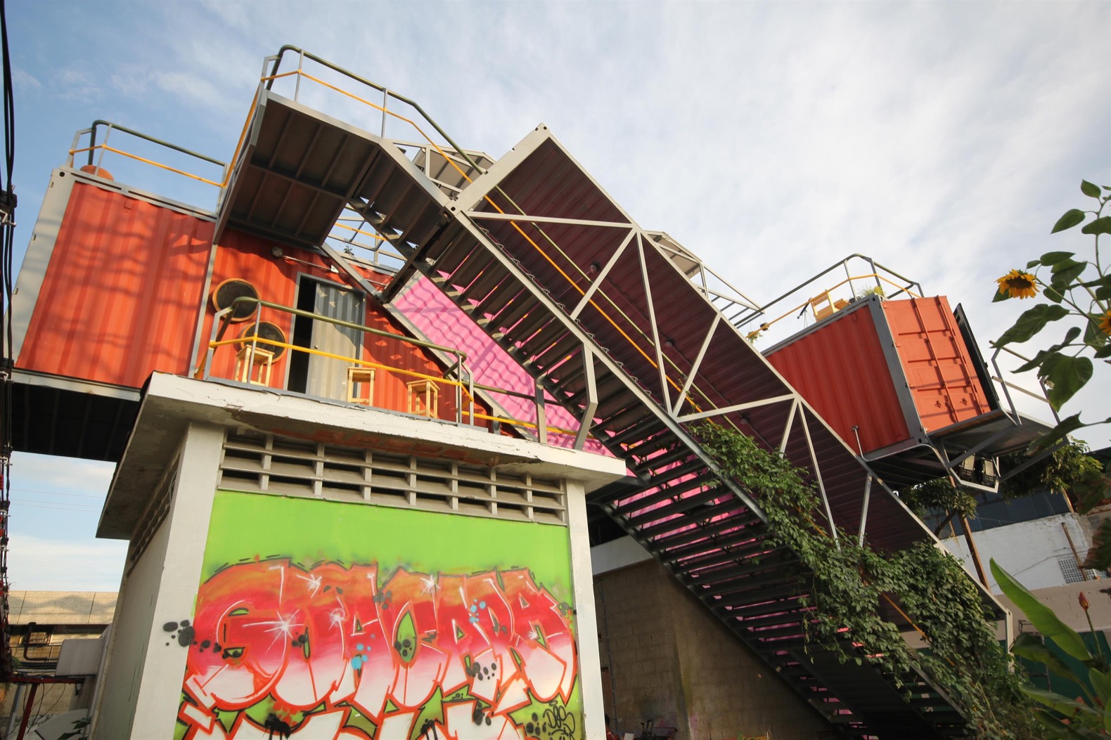 Colorful shipping container building with graffiti and staircase.