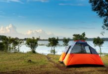 A tent on a grassy hill by a body of water Description automatically generated with low confidence