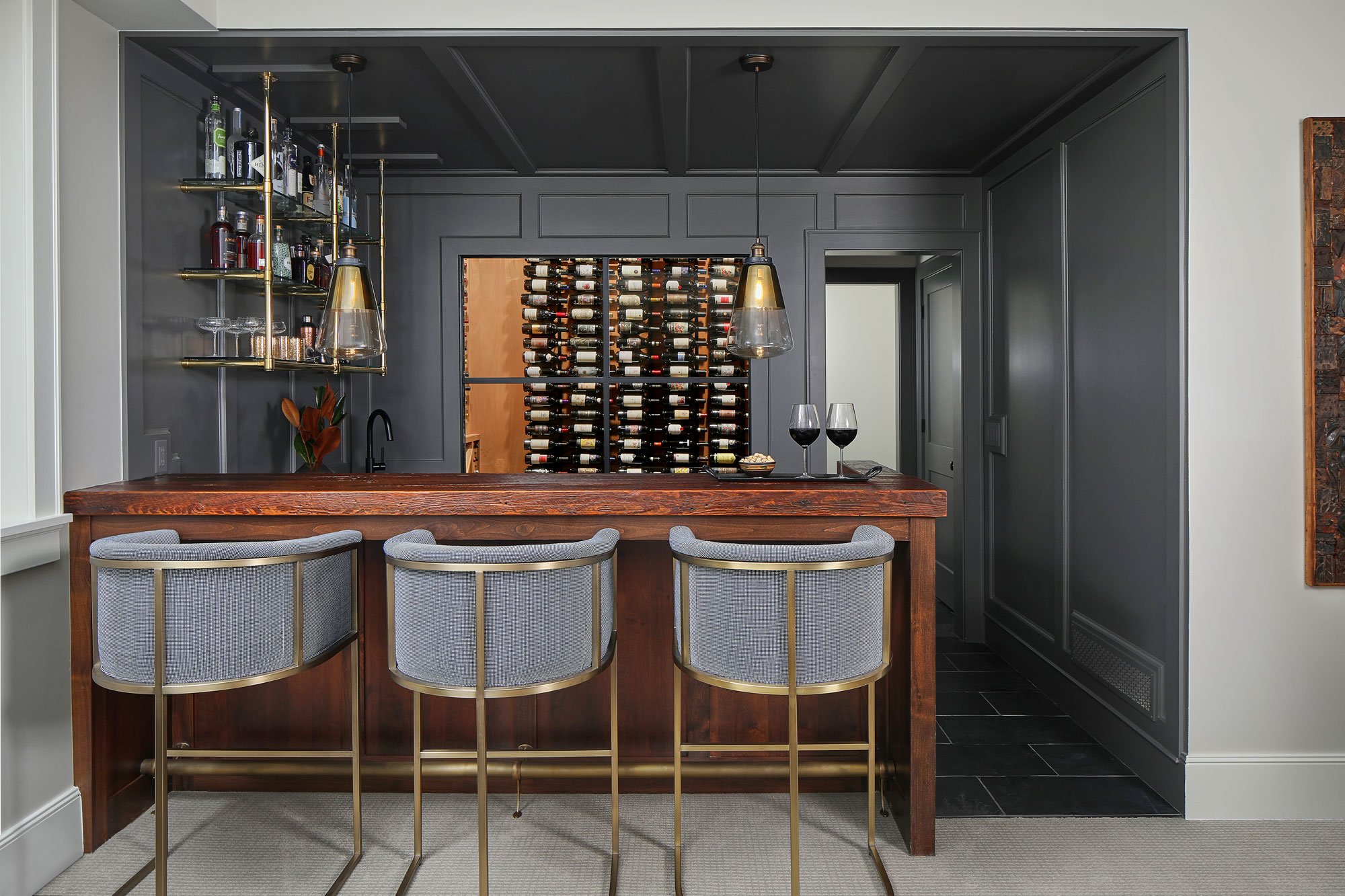 Modern home bar with wine storage and pendant lighting.