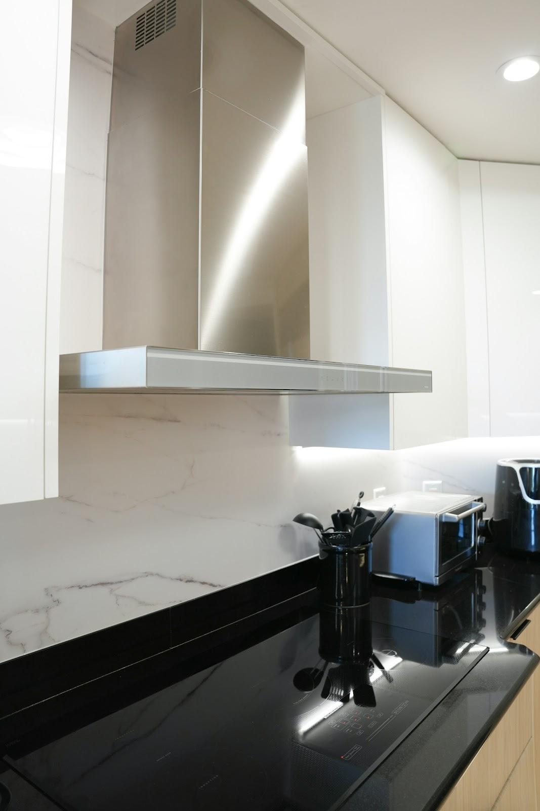 Modern kitchen with stainless steel range hood and appliances.